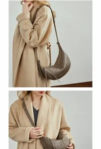 Detail view of a tan leather crescent shoulder bag styled with a khaki wool coat