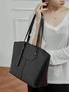 Minimalist black vegetable tanned leather tote bag for women showing a stylish side view