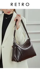 Detalle de bolso bandolera de cuero marrón oscuro con borlas sobre blazer blanco