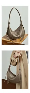 Detail of taupe crescent leather bag showing litchi grain texture and adjustable strap