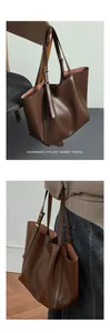 Detail of a large brown leather tote bag showing adjustable straps and textured finish