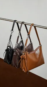 Vista detallada de bolsos de hombro de cuero en tres colores con borlas decorativas