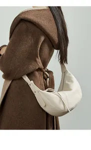 Detailed macro view of the creamy white pebbled leather texture and hobo bag's adjustable strap
