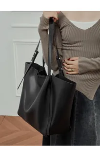 Detail of a large black leather tote bag with silver buckle and adjustable shoulder strap