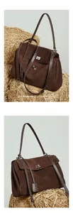 Close-up of vintage dark brown suede tote with silver metal clasp and leather strap