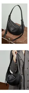 Detail of black lychee grain leather crescent bag with adjustable strap and silver zipper