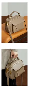 Détail d'un sac à main en cuir taupe avec double fermeture éclair et finitions bronze