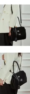 Close-up of matte black leather tote bag with silver twist locks on white suit
