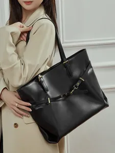 Classic black leather tote bag with gold buckle detail shown on a stylish model