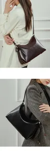 Detalle de bolsos de hombro de cuero negro y marrón con lazo decorativo y acabado brillante