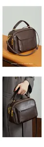 Détail du sac à main en cuir marron foncé avec double fermeture éclair et finitions dorées