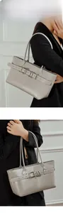 Detail of grey leather tote bag featuring a decorative belted buckle and minimalist handles