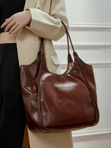 Grand sac cabas en cuir marron chocolat avec finition cirée porté à l'épaule par un mannequin