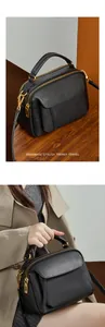 Détail d'un sac en cuir noir grainé avec ferrures dorées et double fermeture éclair
