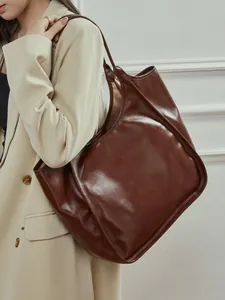 Sac fourre-tout en cuir marron foncé porté par un mannequin dans un cadre de bureau