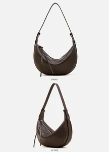 Detail of coffee brown leather crescent bag showing natural lychee grain and strap