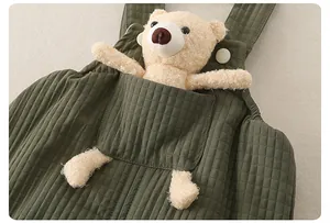 Dettaglio salopette trapuntata neonato verde scuro con orsetto di peluche nella tasca frontale