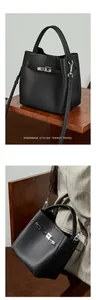 Gros plan du sac seau en cuir grainé noir avec boucle argentée et bandoulière amovible