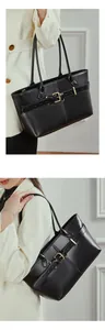 Close-up of the black leather tote bag featuring a gold buckle belt detail and sleek texture