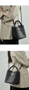 Détail du sac seau en cuir grainé noir avec boucle argentée et bandoulière amovible