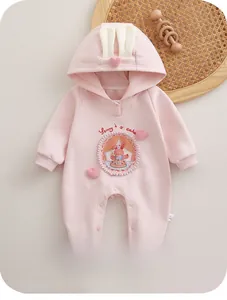 Détail d'une grenouillère rose pour bébé avec oreilles de lapin et motif de dessin animé