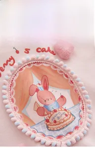 Détail de grenouillère bébé en coton rose avec broderie lapin et mini pompons décoratifs