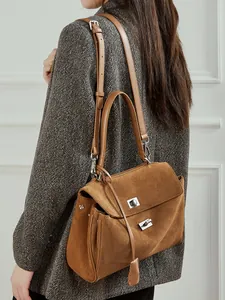 Brown suede tote bag with metal lock and dual straps on a model wearing a grey wool coat
