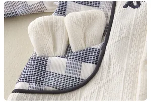 Dettaglio della tutina neonato con cappuccio in maglia jacquard e orecchie di animali