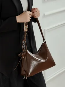 Bolso hobo de cuero marrón oscuro brillante con herrajes plateados en una modelo