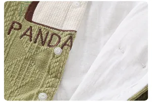 Macro detail of green waffle knit baby romper with panda embroidery and resin snaps