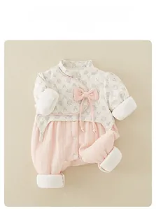 Close-up of floral baby romper featuring a pink bow, tassel details, and plush velvet cuffs