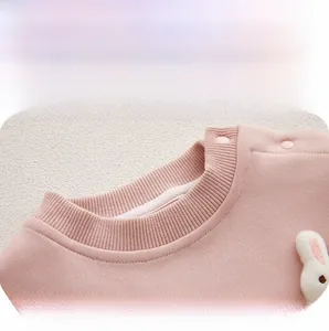 Dettaglio tutina rosa per neonata con morbida trama a maglia e grazioso coniglio in peluche