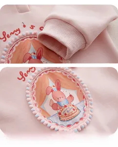Détail d'un body rose pour bébé avec écusson lapin brodé et poignets côtelés