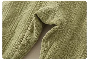 Detail shot of newborn knit romper showing moss green textured diamond weave fabric
