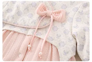 Detail of baby winter outfit featuring floral fabric, pink knit texture and pearl bow