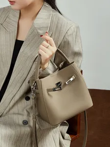 Sac seau chic en cuir grainé gris éléphant avec fermoir argenté porté par un mannequin femme