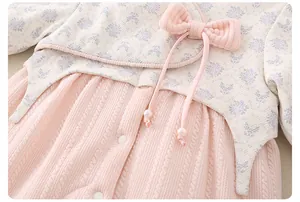 Detailed view of baby floral cotton romper with pink bow and pearl accents for winter