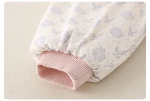 Detail of floral baby romper cuff with soft pink ribbing and delicate cotton fabric texture