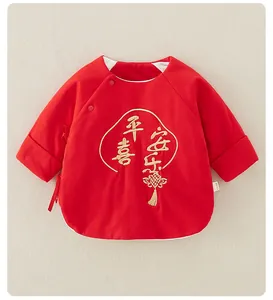 Détail de la broderie dorée et du nœud chinois sur le haut en coton rouge pour bébé