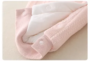 Detailed close-up of pink knit baby romper showing soft faux lamb wool lining and white buttons