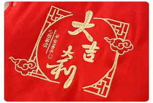 Détail du haut festif pour bébé en coton rouge avec broderie dorée et bouton pression