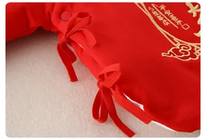 Détail du haut pour nouveau-né en coton rouge avec broderie dorée et rubans