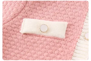 Dettaglio di pagliaccetto in maglia rosa con trama a nido d'ape e bottone a perla