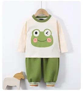 Detail view of baby clothes set with green frog print shirt and matching green pants