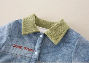 Detail of infant denim romper with light blue wash, green knit collar and embroidery