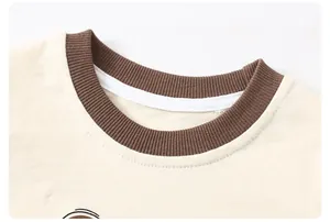 Detailed close-up of a child's beige cotton tee with a brown ribbed knit neckline