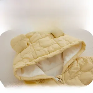 Detail of baby hooded quilted jacket with bear pattern and warm faux shearling lining