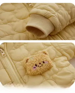 Detail of ribbed cuffs and 3D plush bear patch on yellow quilted baby romper
