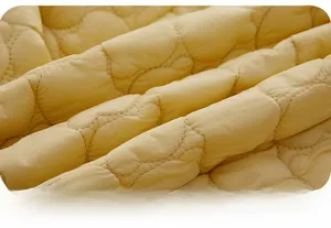 Detailed close-up of yellow quilted fabric with soft wavy stitching for infant clothing