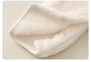 Dettaglio ravvicinato della tutina per neonati in flanella color crema con bottoni a pressione